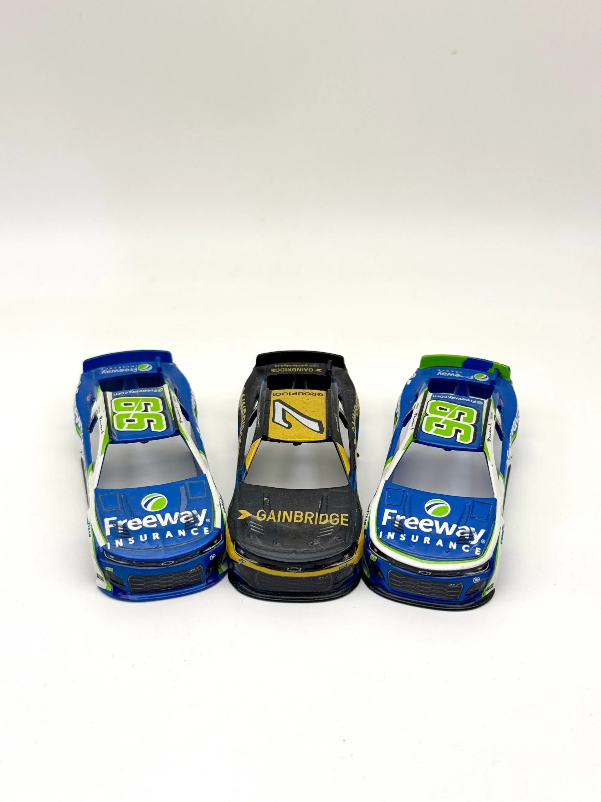 Three decorated model race-car body shells with sponsor-style graphics