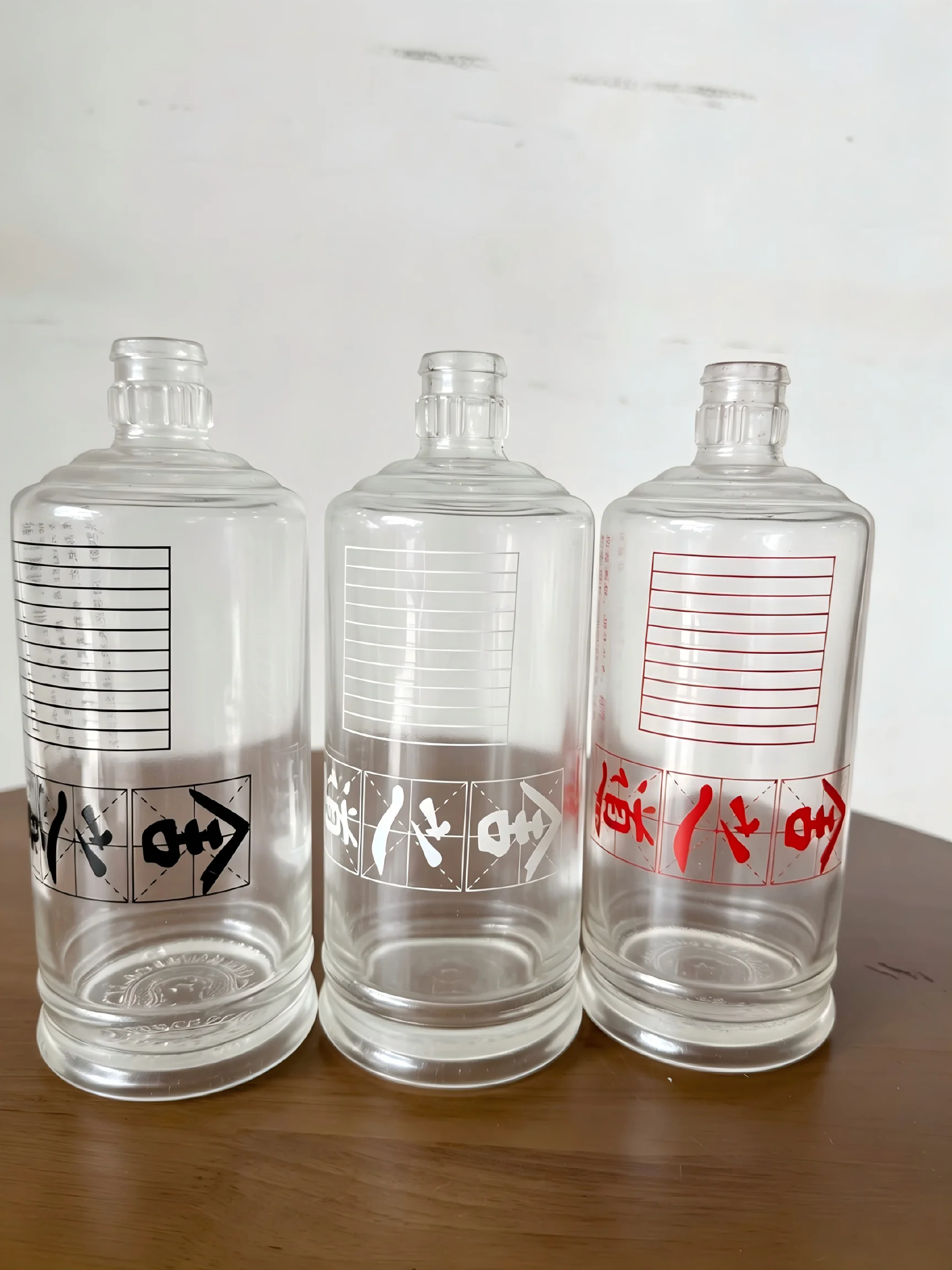 Three clear glass bottles with black, white and red printed designs