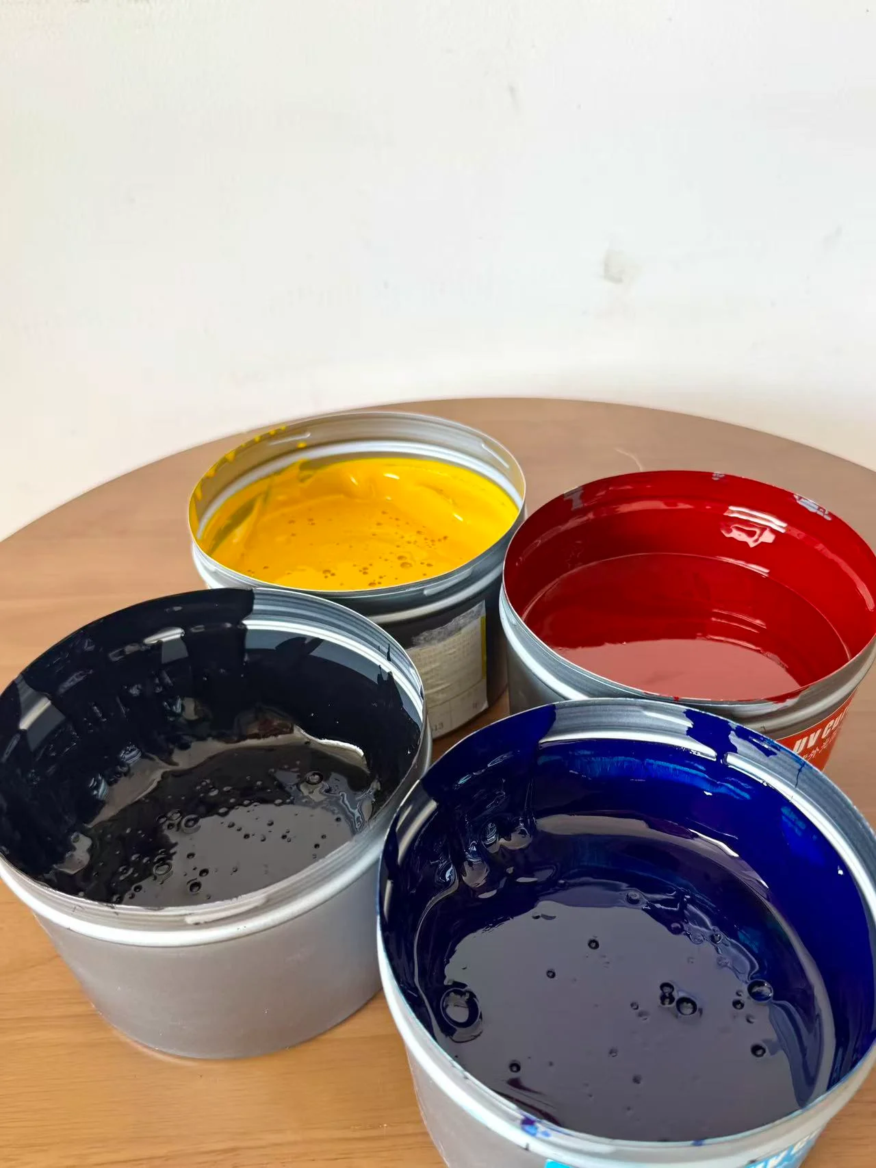 Open cans of yellow, red, black and blue glass printing inks